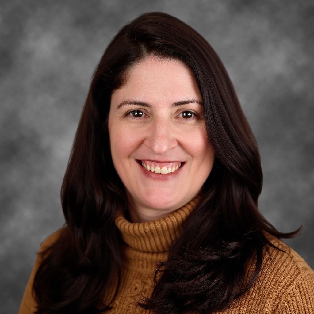 Smiling woman with dark hair in a brown turtleneck, gray background.