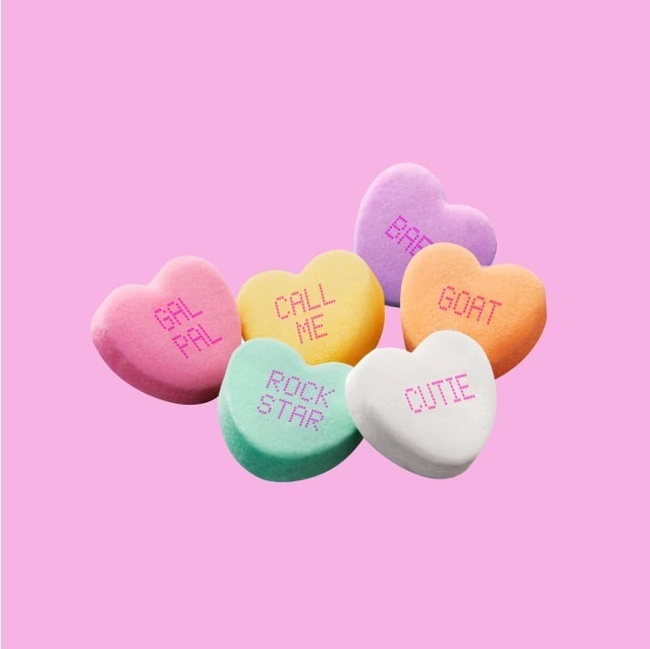 Colorful conversation hearts with text like "GAL PAL", "BAE", "GOAT", "CUTIE" on a pink background.