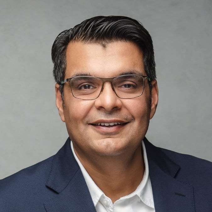 Professional headshot of a smiling man wearing glasses.