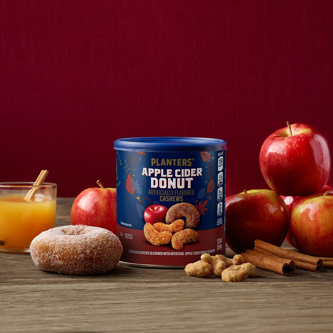 Planters Apple Cider Donut Cashews can, apples, cider, donut, and nuts on a wooden table.