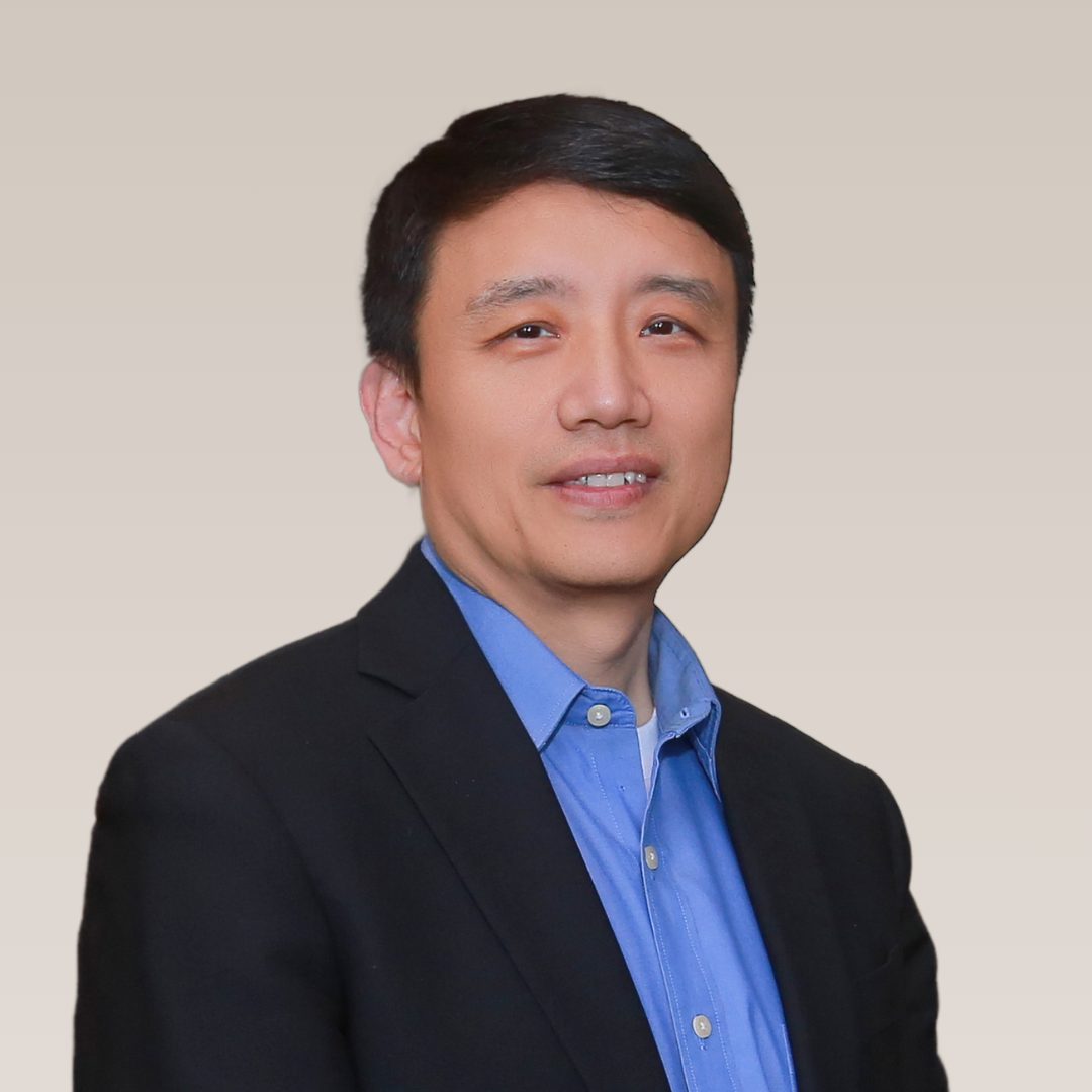 Smiling East Asian man in a blue shirt and black blazer.