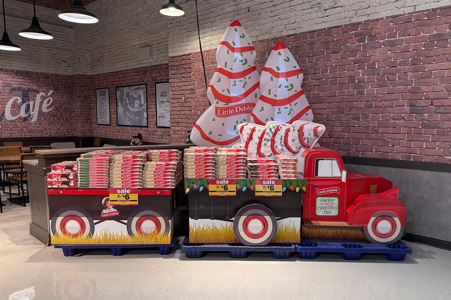 Little Debbie Christmas snack display with inflatable trees, a red truck, and 2/$6 sale.