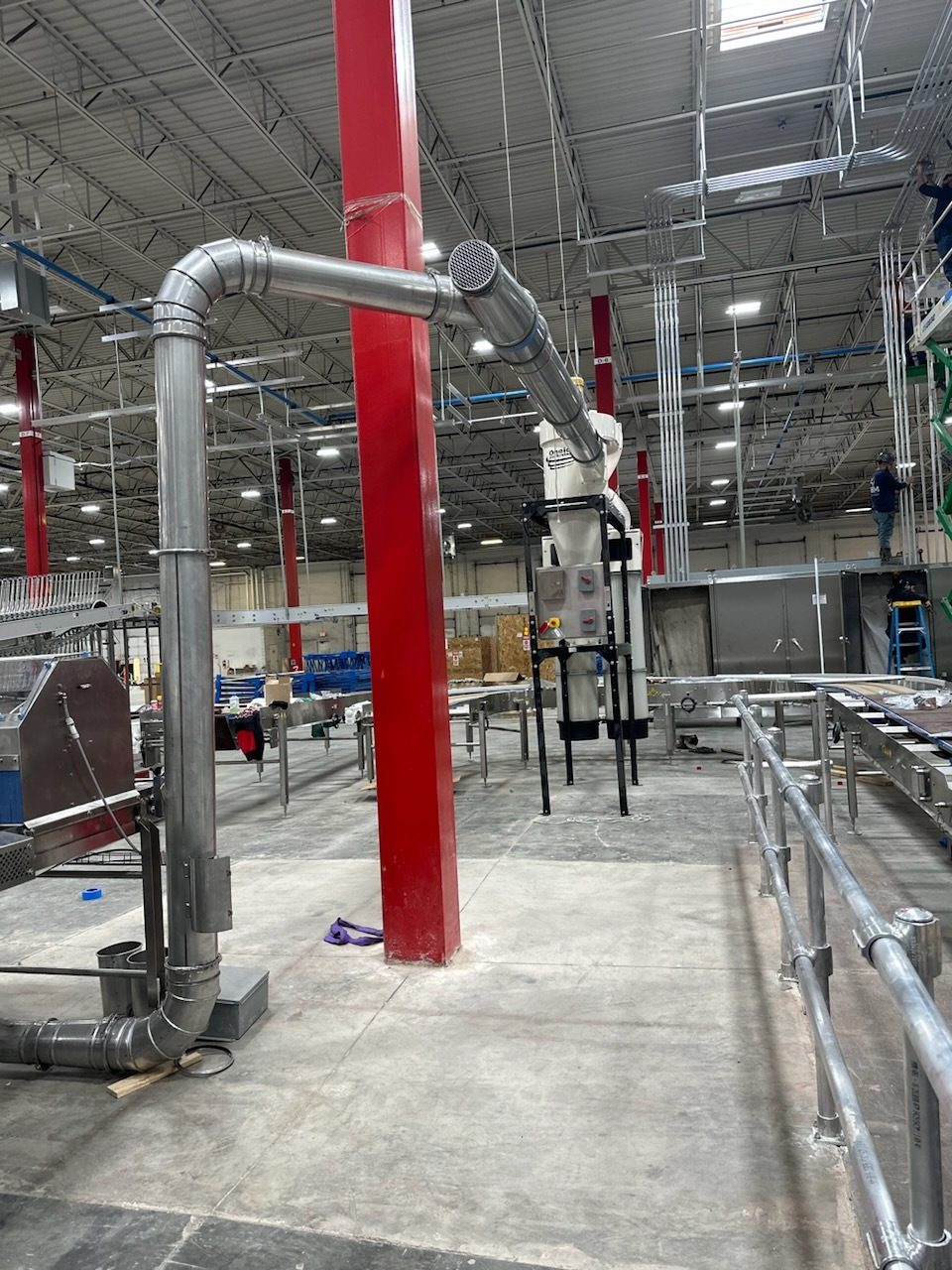 Industrial interior with extensive silver ductwork, red columns, and factory equipment.