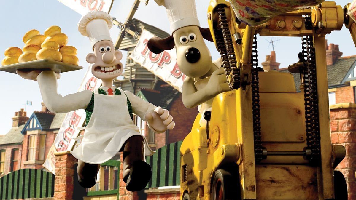 Wallace and Gromit, dressed as bakers, Wallace holding buns, and Gromit on a yellow machine.