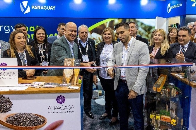 People cutting a ribbon at a Paraguay and Alpacasa trade show booth.