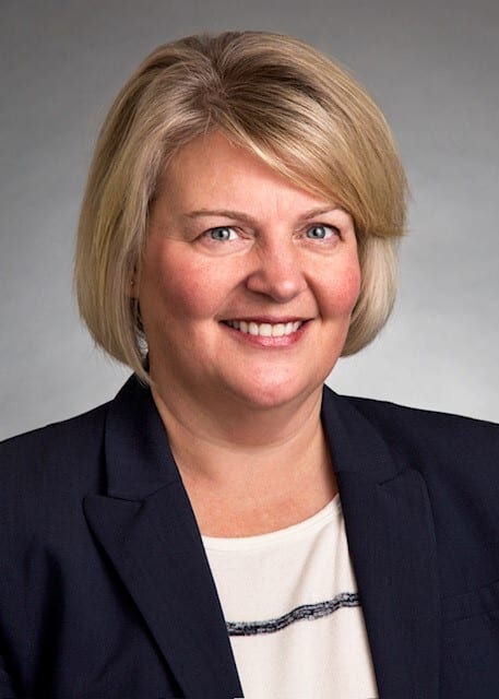 Portrait of a smiling blonde woman in a navy blazer.