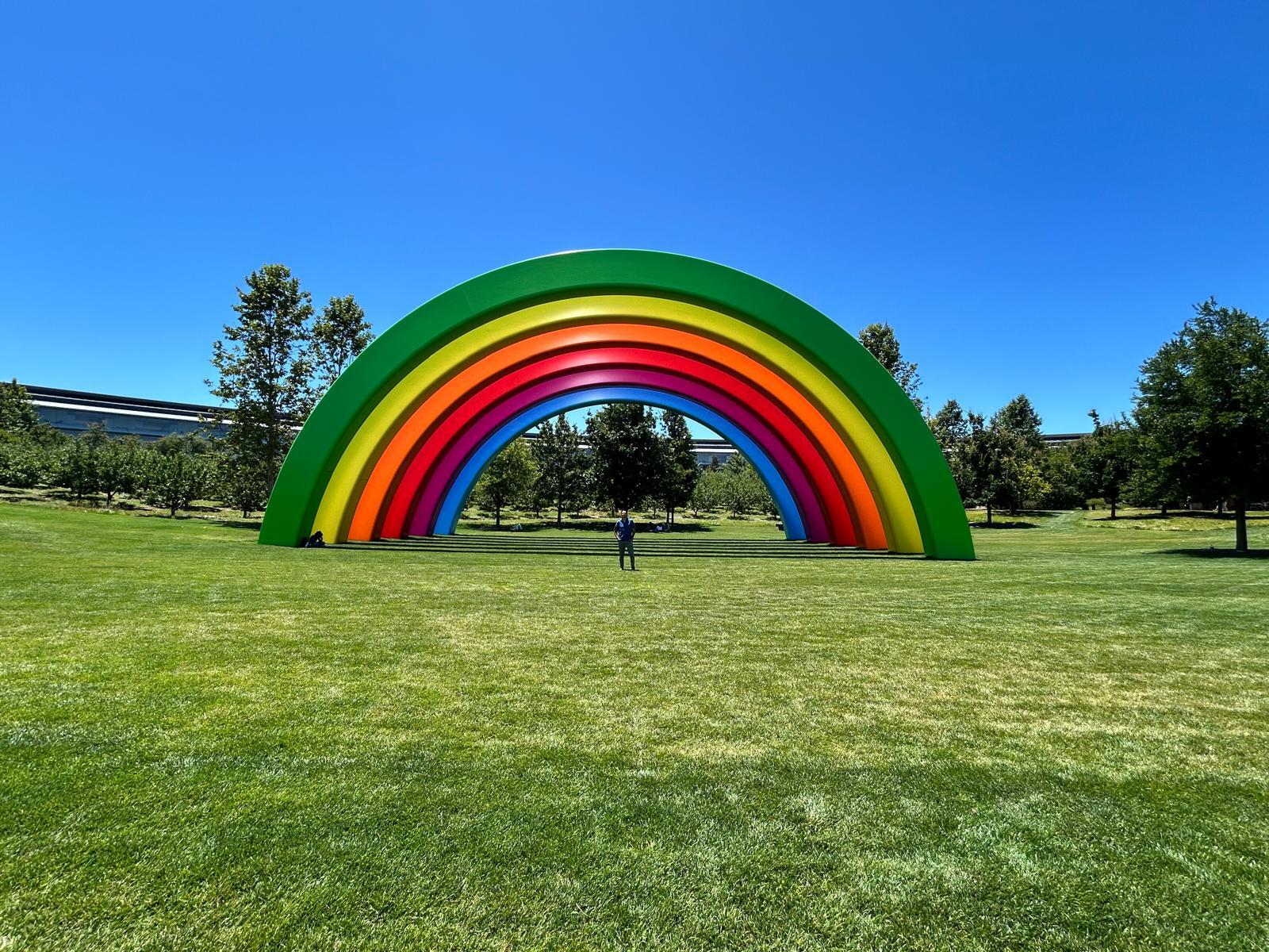 Giant colorful rainbow arch in a grassy field with a person.