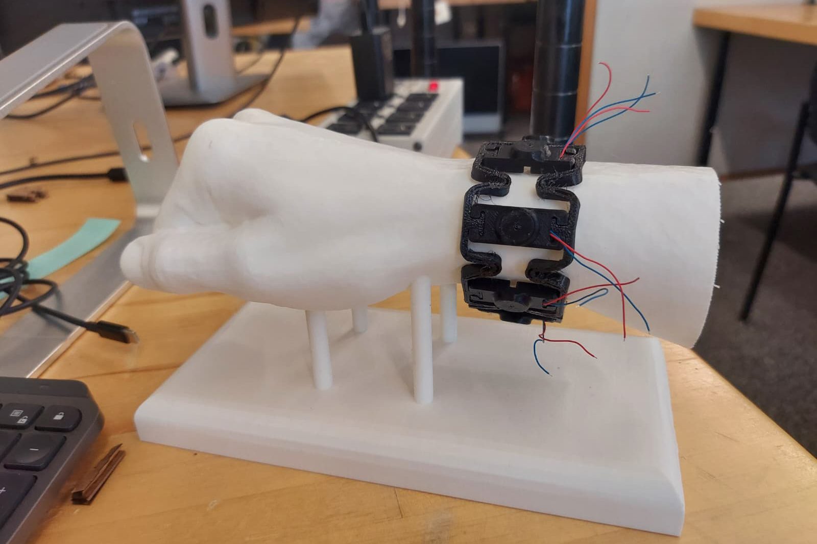Wearable device prototype on a 3D-printed hand model with visible wires.