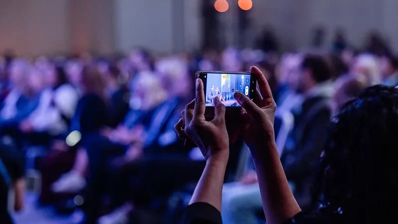 An attendee records a presentation on a smartphone