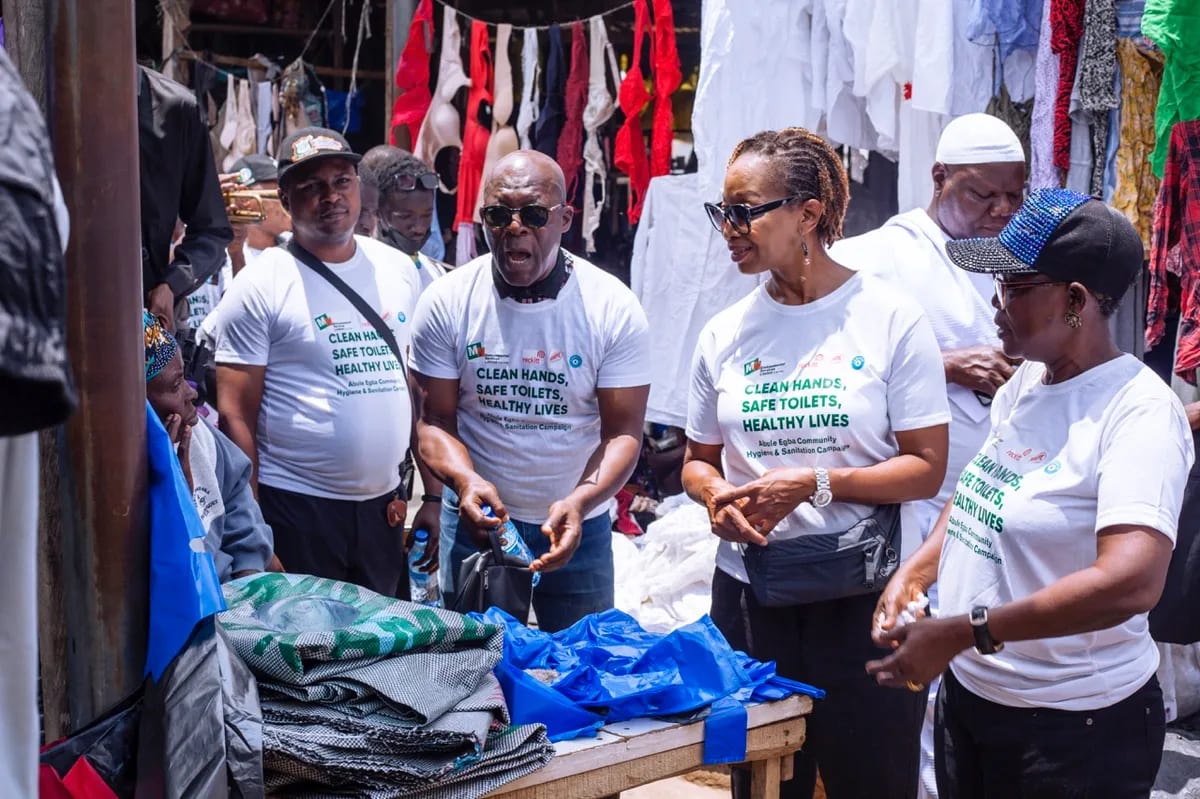 People in "Clean Hands, Safe Toilets, Healthy Lives" t-shirts at a market.