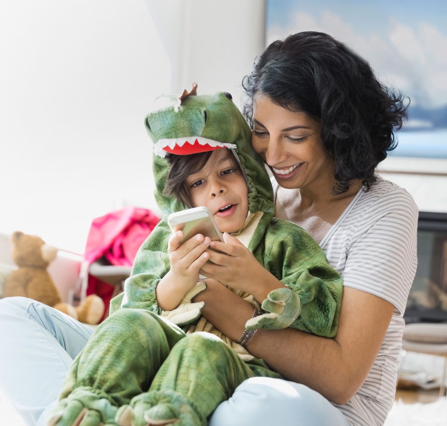 Mother and child in dino costume watch phone together.