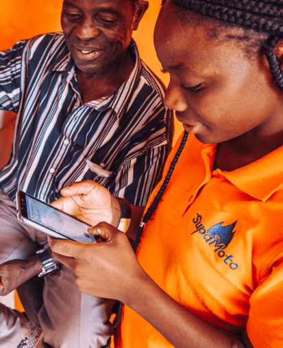 Two people looking at a smartphone, woman in SupaMoto shirt.