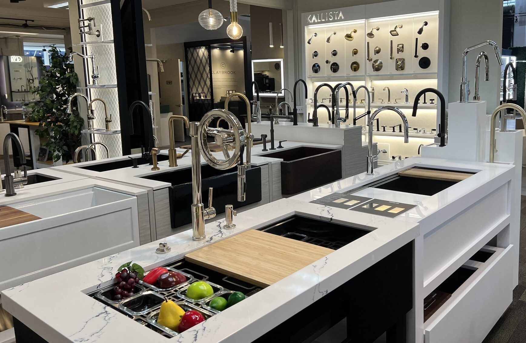 A showroom displaying a variety of modern kitchen and bathroom faucets, sinks, and fixtures on white countertops.