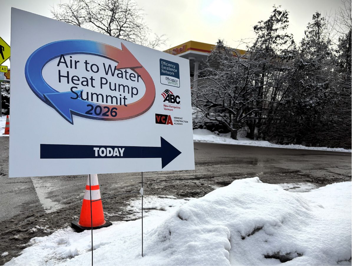 A white sign for the 'Air to Water Heat Pump Summit 2026' pointing right, set in a snowy outdoor scene.