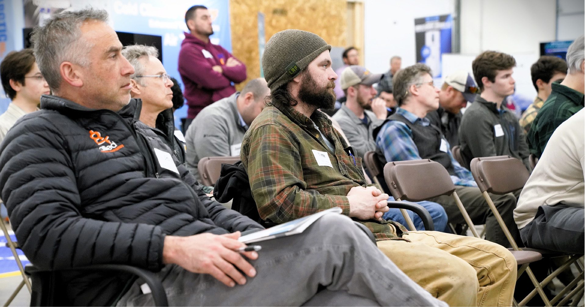 Men attentively listening to a presentation or lecture in a casual setting.