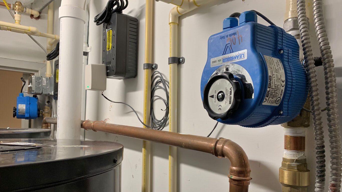 Utility room plumbing: water heater, Valbia LEAKDEFENSE valve, various pipes, and smart home tech.