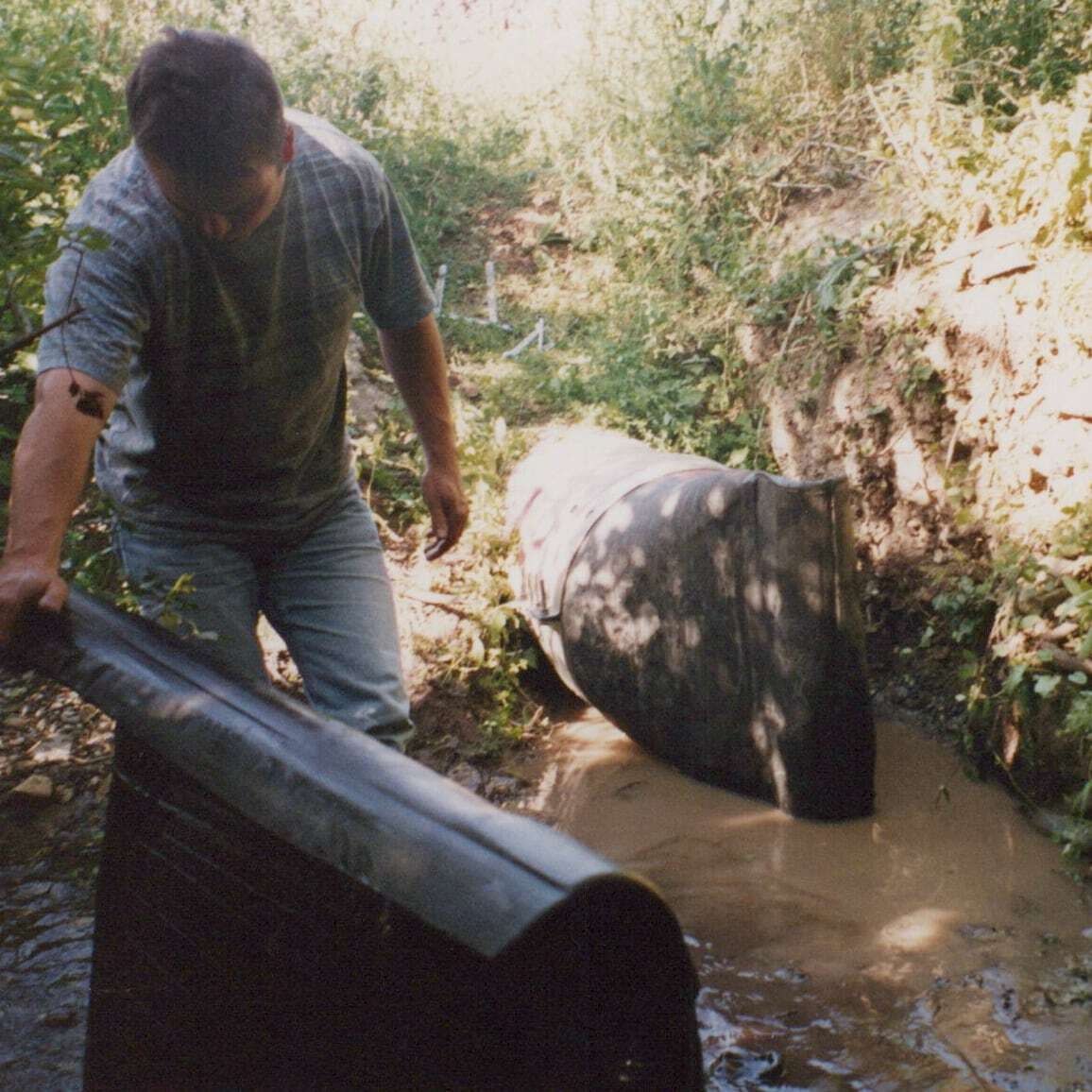 Mark Radford installing a rubber duckbill check valve at a silted ditch outfall in Ireland, 1992