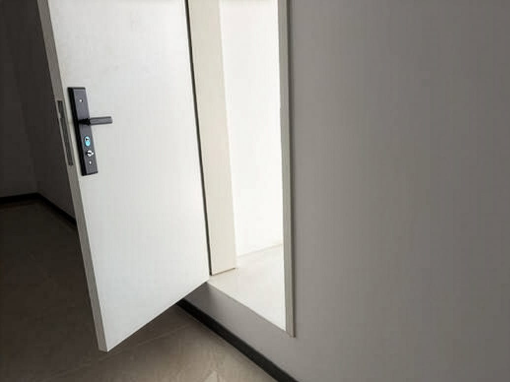 A modern white door with a black smart lock slightly ajar, revealing a brightly lit interior space.