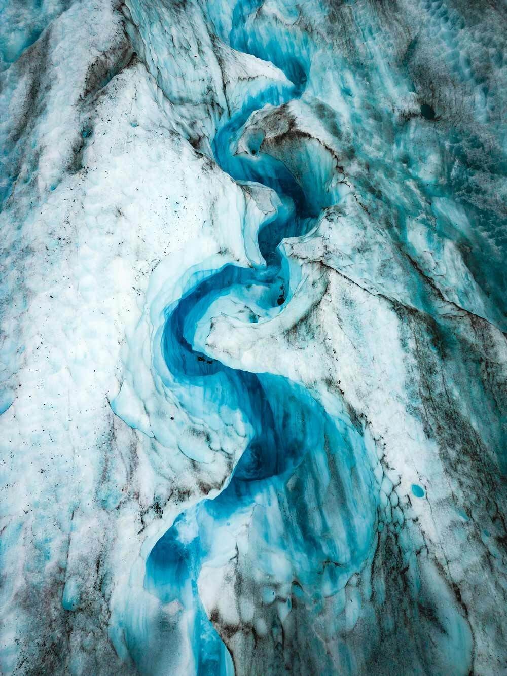 Aerial view: Winding turquoise river in a glacier.