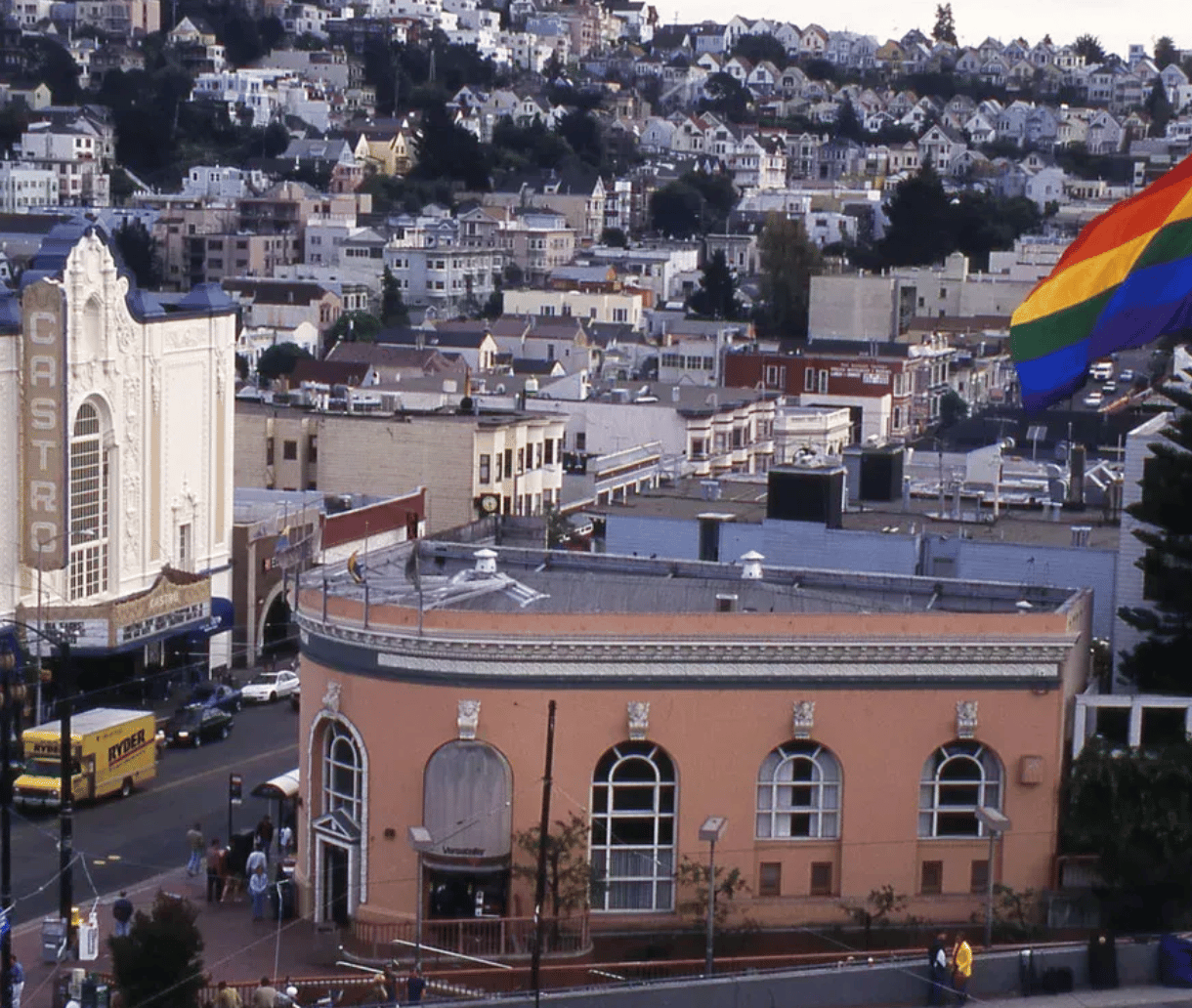 Panoramic view of San Francisco's Castro district, featuring the Castro Theatre, a rounded pink building, and a rainbow flag.