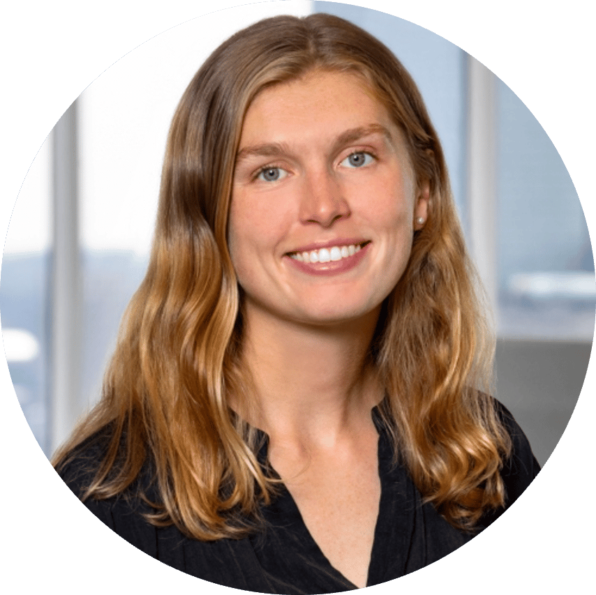 Headshot of a smiling young woman with long, wavy blonde hair and blue eyes, wearing a black shirt.