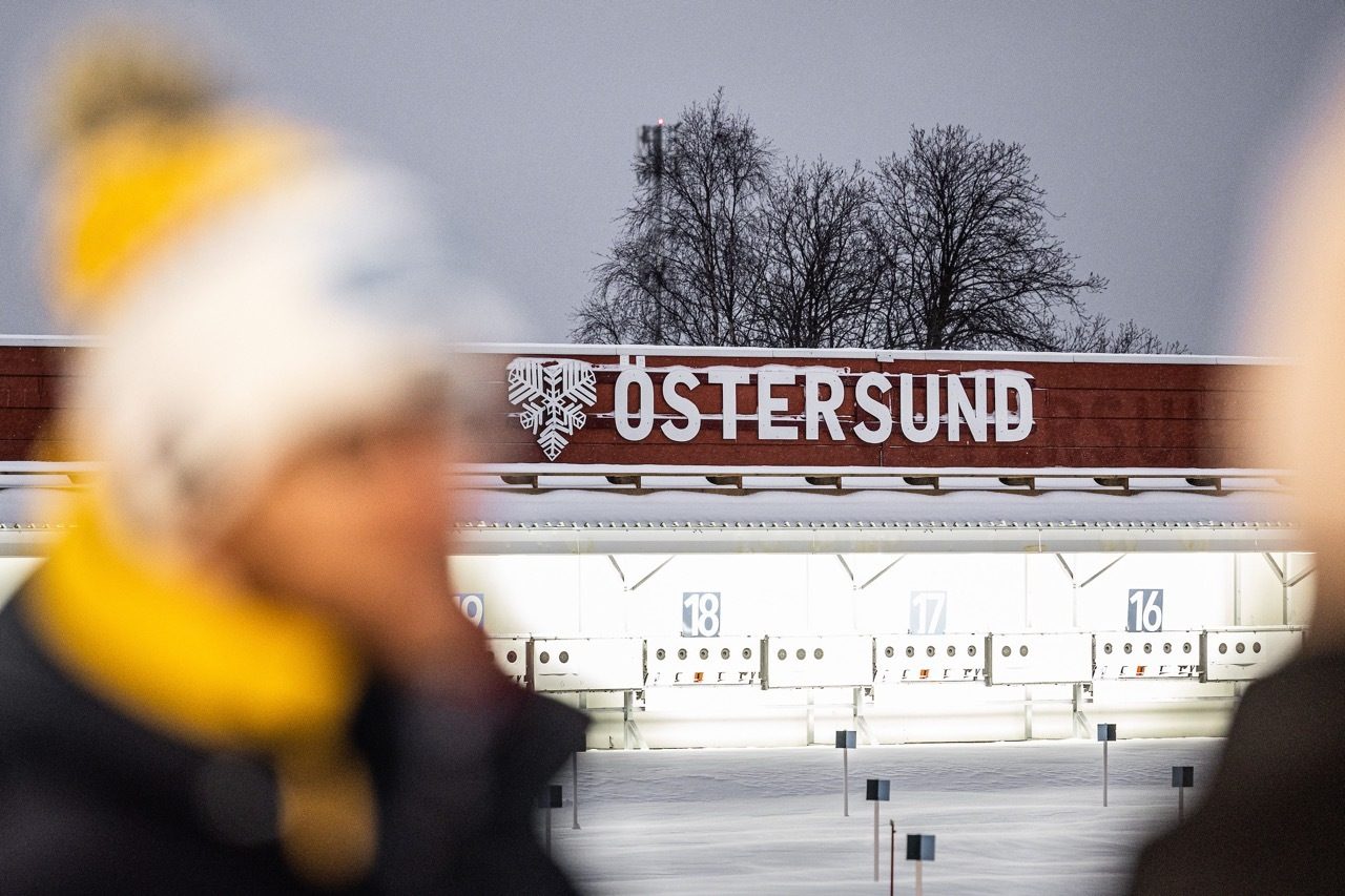 A biathlon shooting range in Östersund, Sweden, with targets, a large sign, and snow-covered trees.