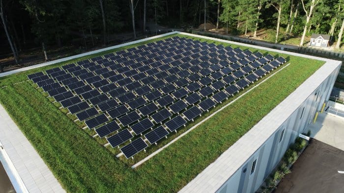 Aerial view of a large array of solar panels on a lush green roof, symbolizing sustainable energy solutions.