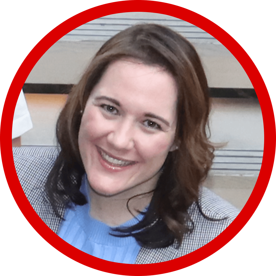 Smiling woman with brown hair in a blue top and checkered blazer.