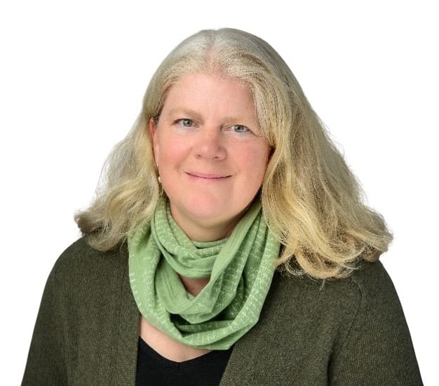 Smiling woman with long blonde hair and green scarf.