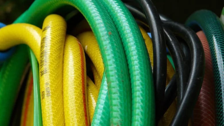 Close-up of coiled garden hoses in green, yellow, black, and red.