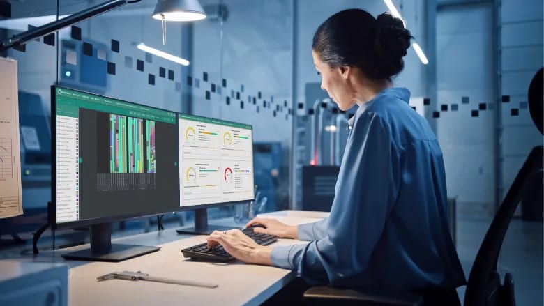 Woman analyzing data on dual monitors in a modern lab or office setting.