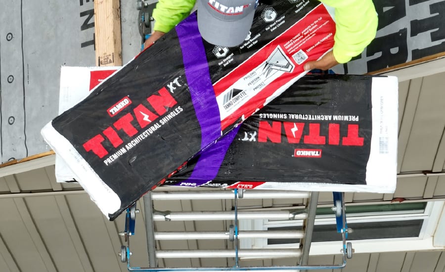 Worker lifting Tamko Titan shingles on a roof hoist.