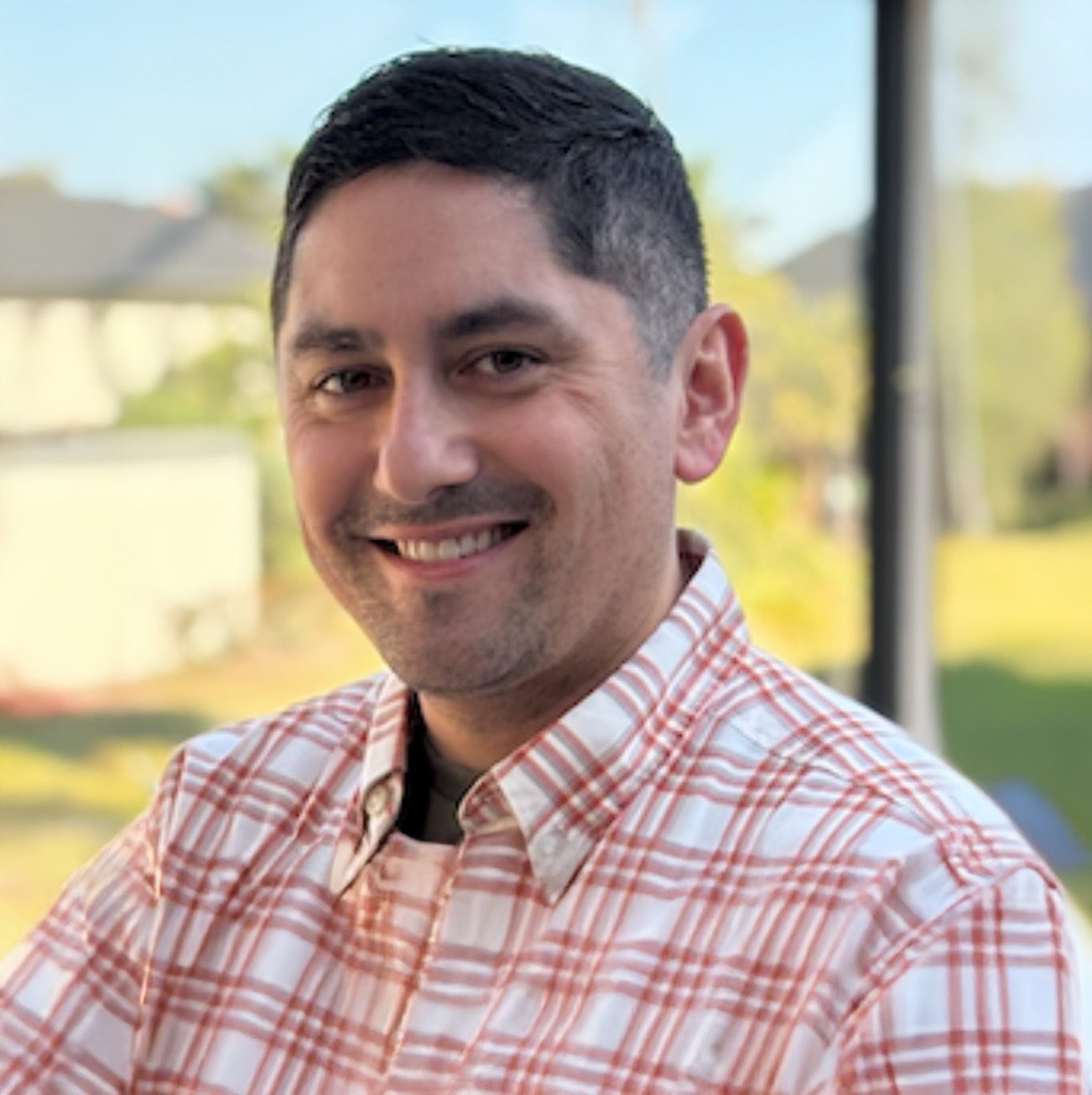 Smiling man in plaid shirt.