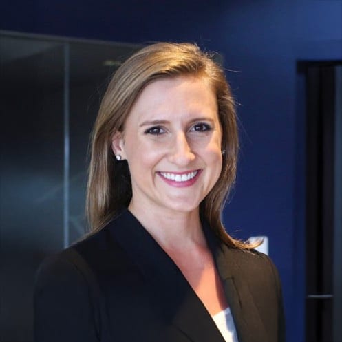 Smiling woman with light brown hair wearing a black blazer.