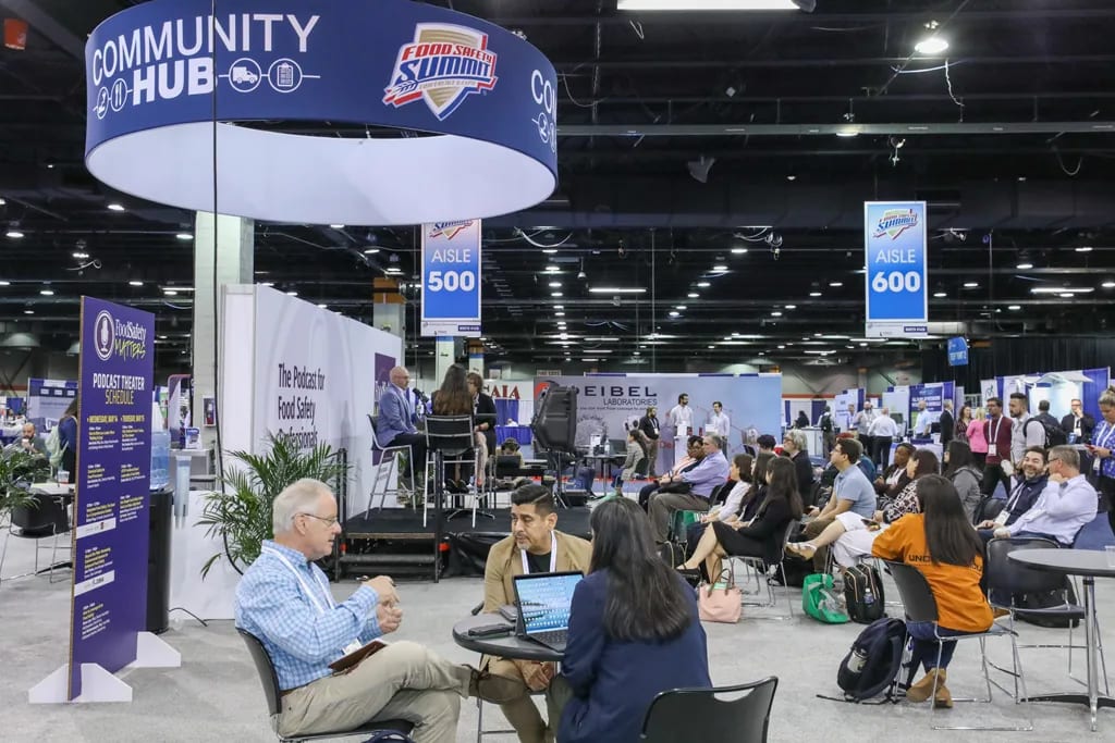 Attendees networking and listening to a podcast session at the Food Safety Summit Community Hub.
