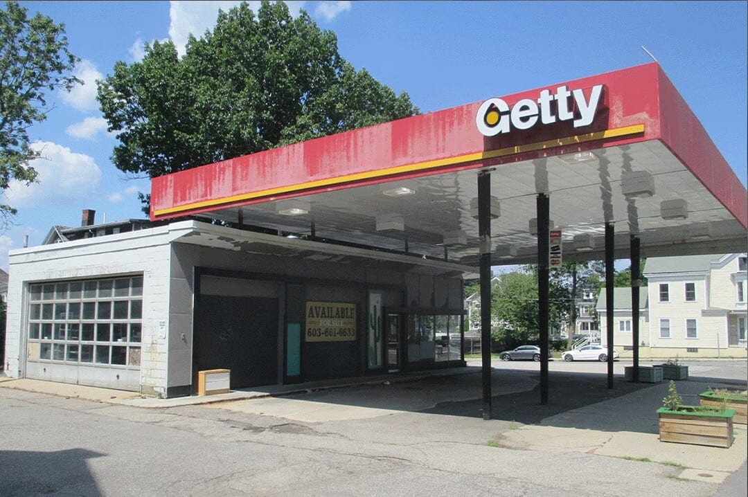 An old, abandoned Getty gas station with a red canopy and an "Available" sign on the building.