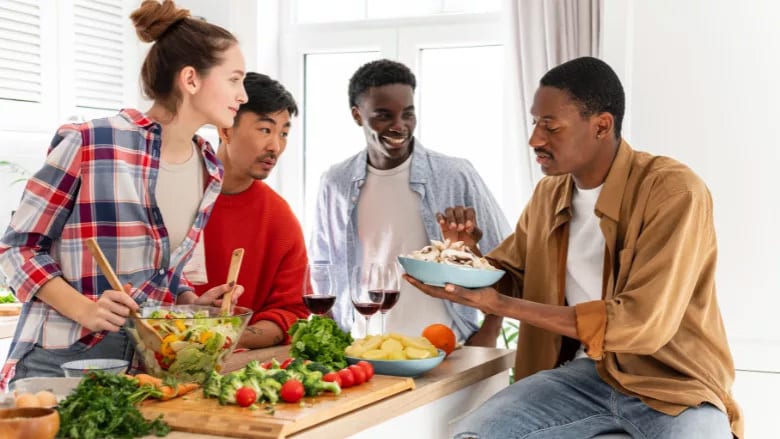 Diverse friends cooking together in a bright kitchen, preparing a healthy meal with fresh vegetables.