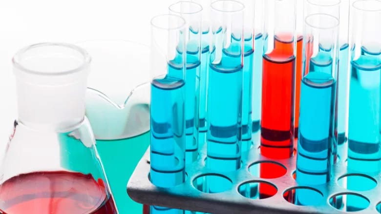 Lab glassware with colorful liquids: flask, beaker, and test tubes in a rack.