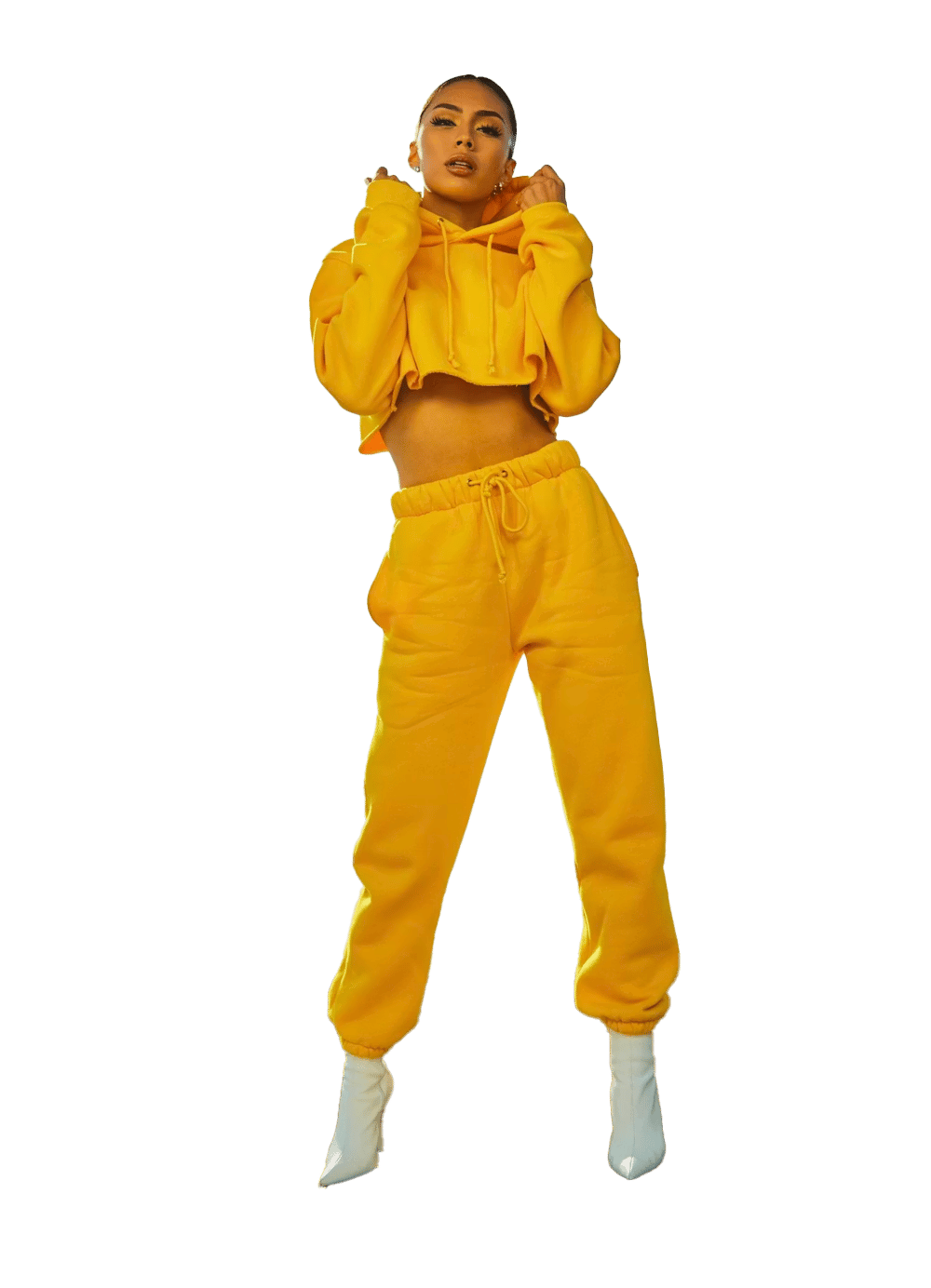 Woman in a vibrant yellow cropped hoodie and sweatpants with white boots, striking a pose.
