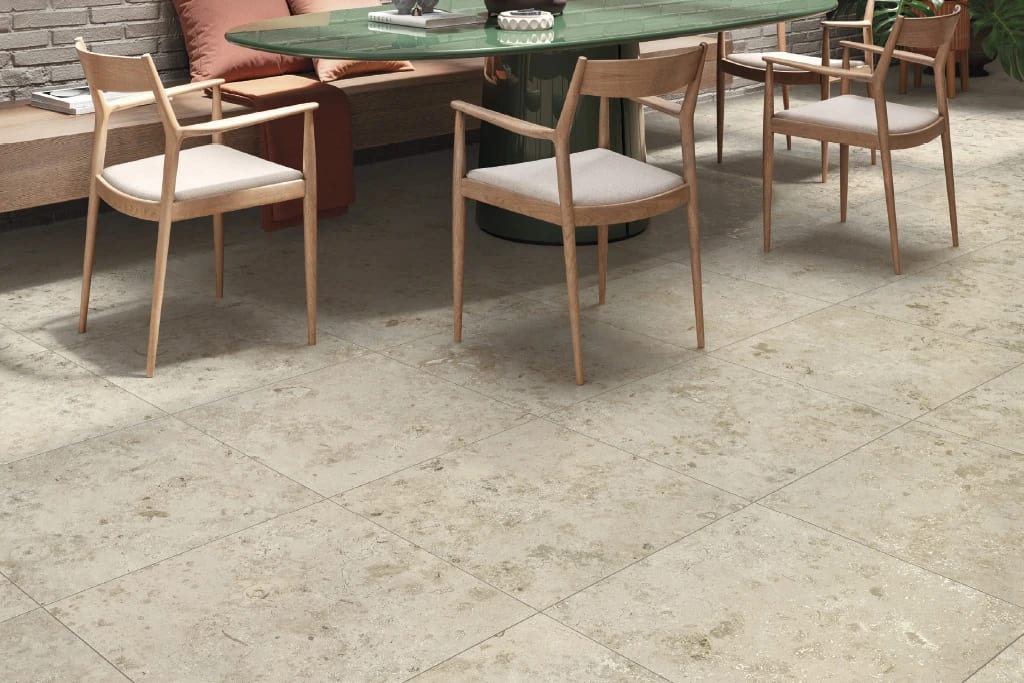 Dining area with green table, wooden chairs, and light stone-look floor tiles.