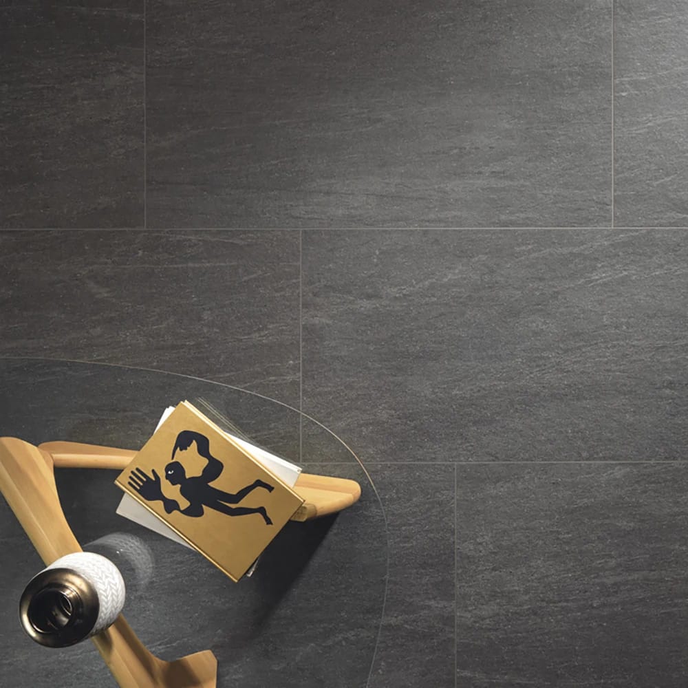Overhead: dark gray tiled floor, glass table with a book and decorative object.