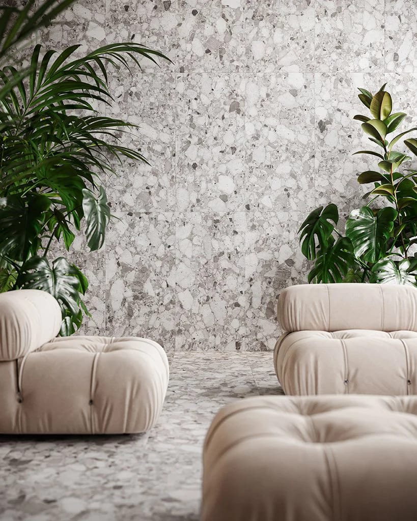 Modern room: terrazzo wall/floor, green plants, and beige tufted sofas.