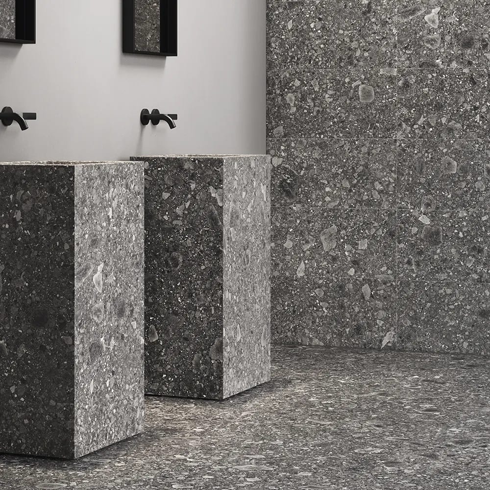 Dark grey terrazzo bathroom with two pedestal sinks.