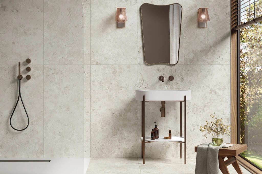 Modern tiled bathroom with shower, sink, mirror, and large window overlooking nature.