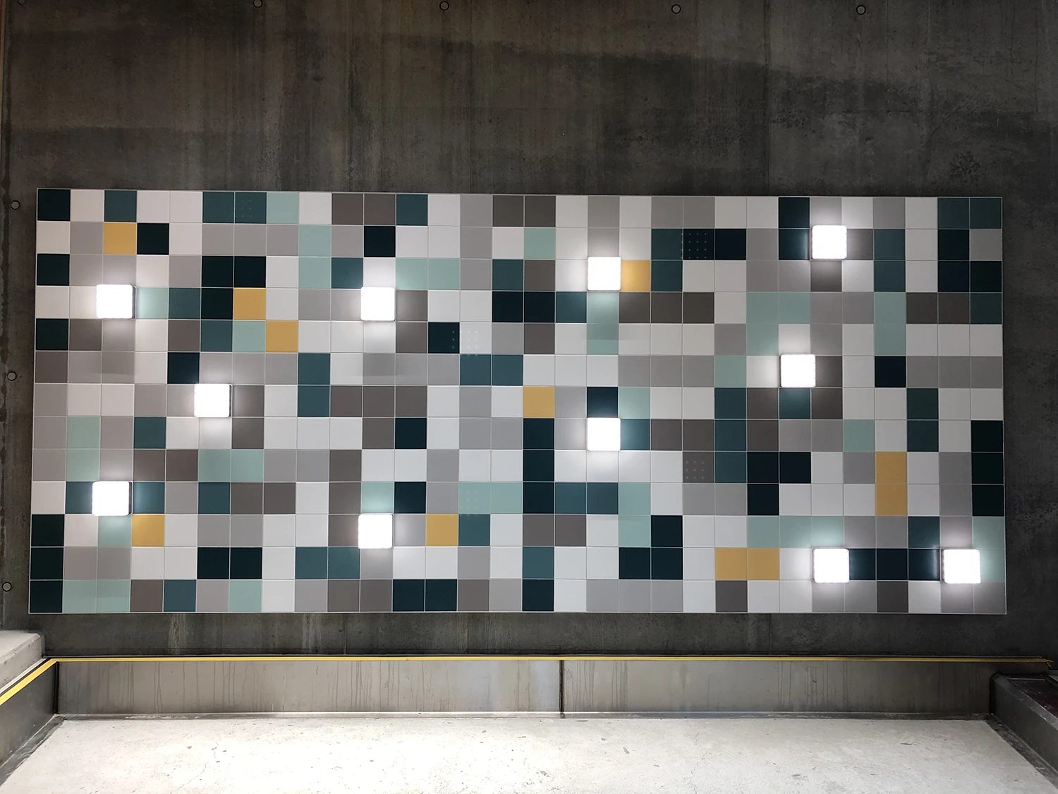 Colorful tiled wall panel with glowing lights against a concrete background.