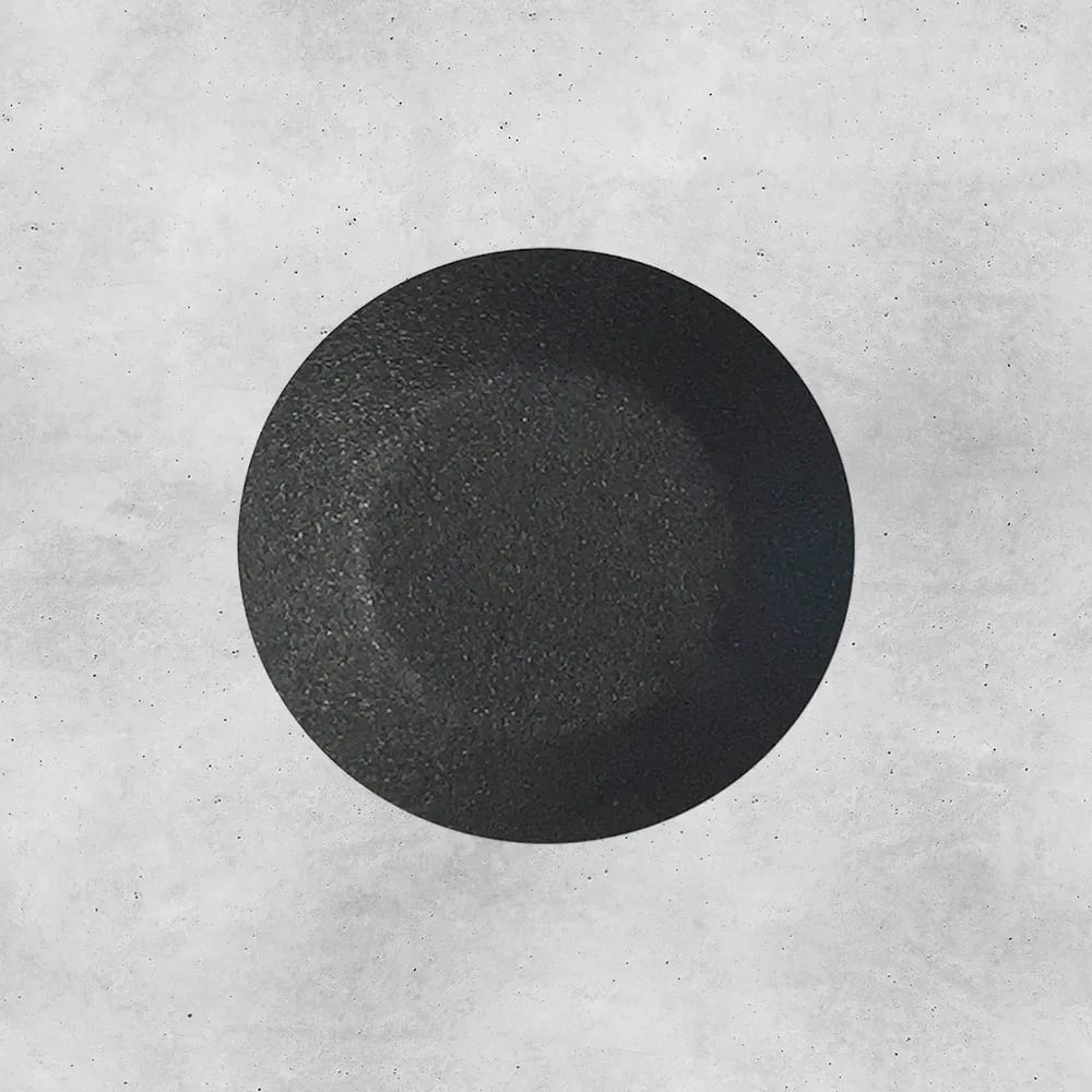 Textured black circle on gray concrete.