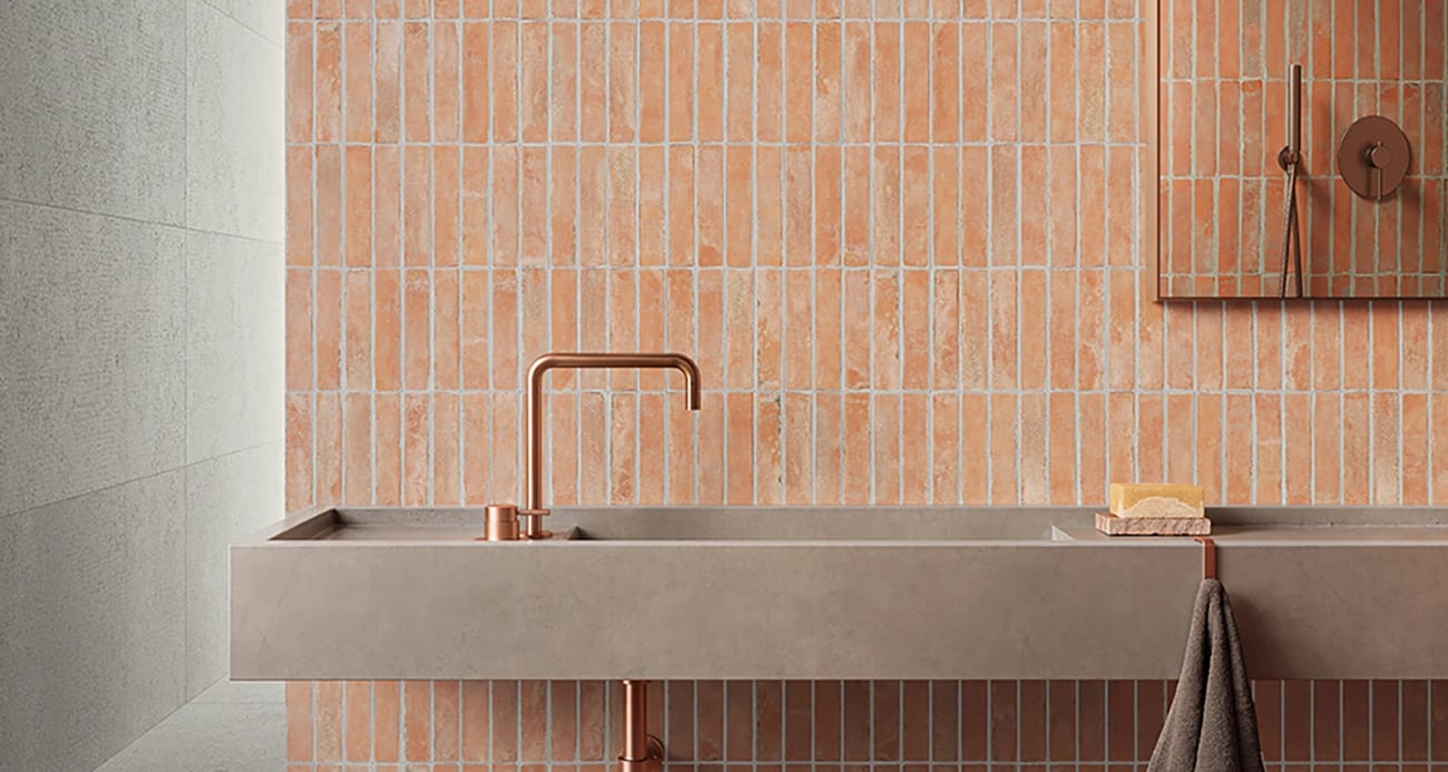 Terracotta tiled bathroom with a concrete sink and copper fixtures.