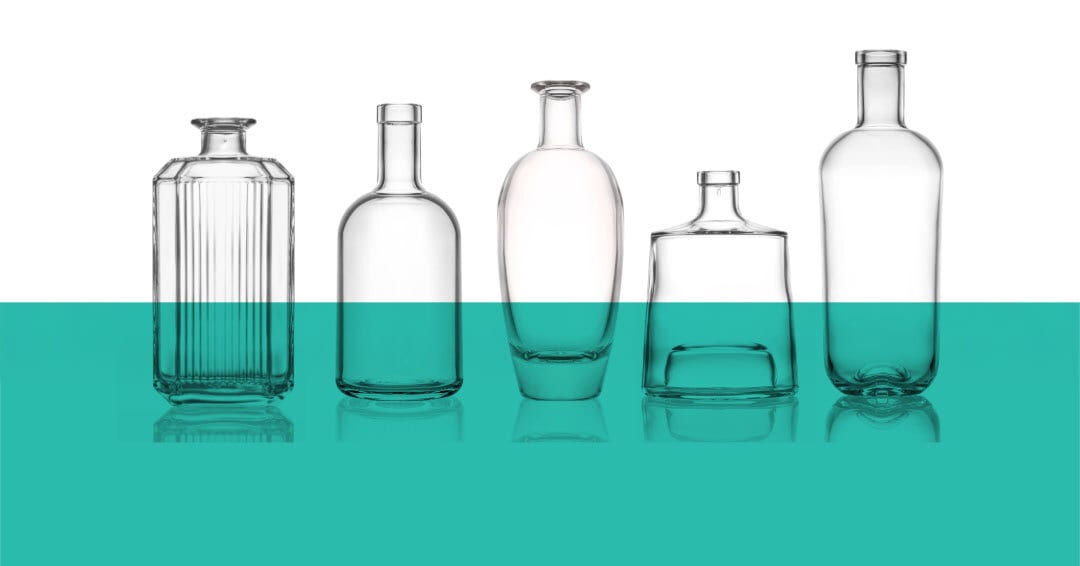 Five empty clear glass bottles of diverse shapes on a reflective teal and white background.