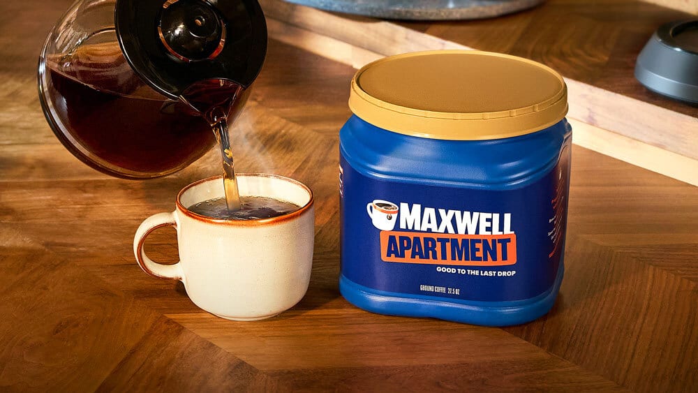 Coffee pouring into a mug next to a Maxwell Apartment coffee container.