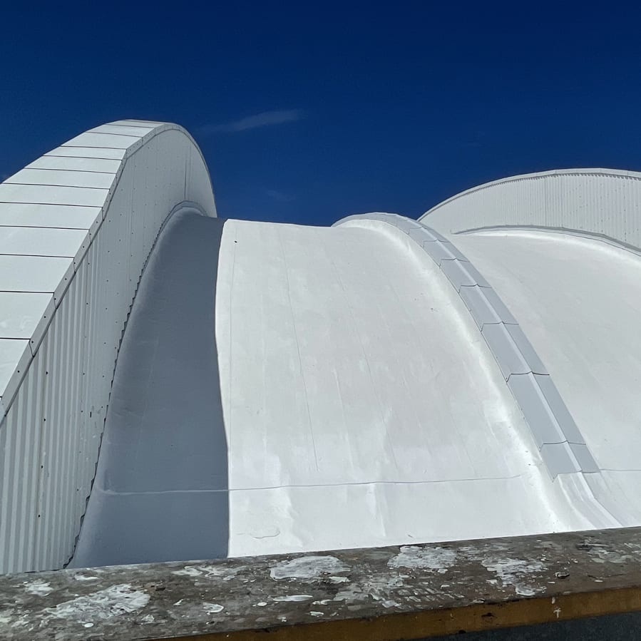 White dramatic curve of a commercial roof with liquid sealant.